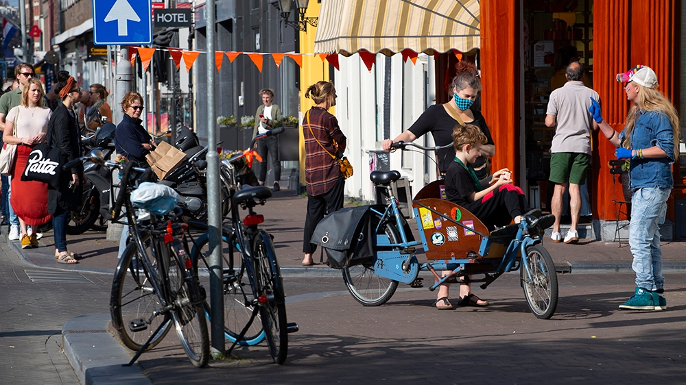 People, some wearing face masks, observe social distancing to prevent the spread of the coronavirus when standing in line to buy traditional King’s Day pastry in Amsterdam, the Netherlands