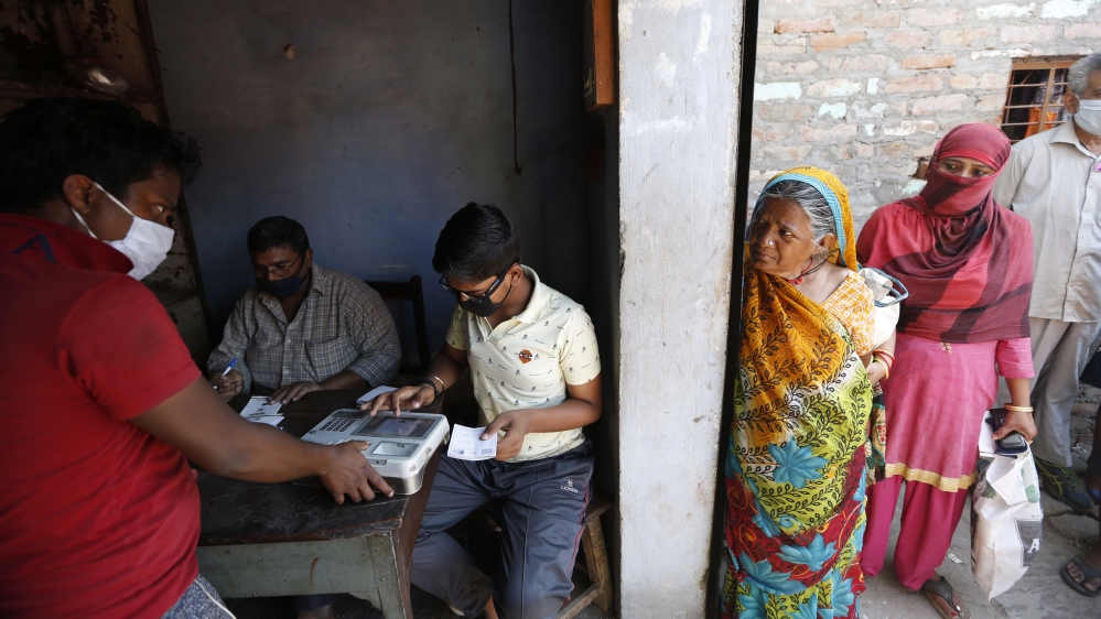 Indians line up to have their fingerprints taken on a biometric machine after purchasing food rations on Thursday.