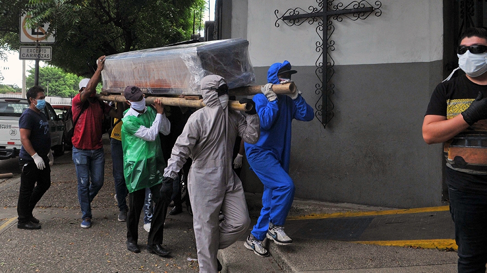 Relatives of a person who died from COVID-19 carry the wrapped coffin in Ecuador