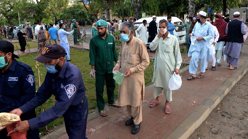 People line up to receive free food as the time to break fast approaches during Ramadan amid a coronavirus lockdown of the Punjab province