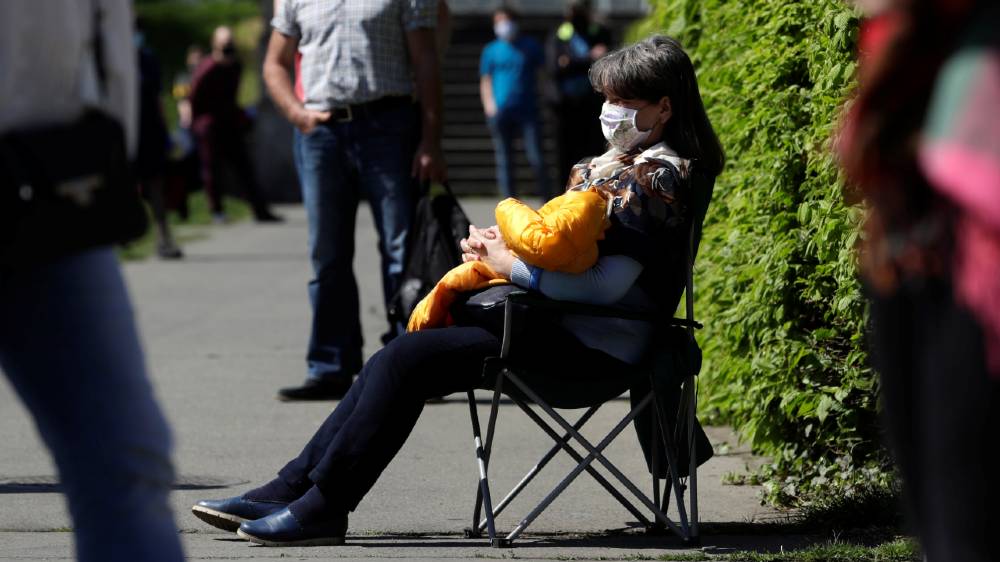 A woman sits on a chair while waiting in line to be tested for the coronavirus as a part of a study about undetected infections in Prague, Czech Republic