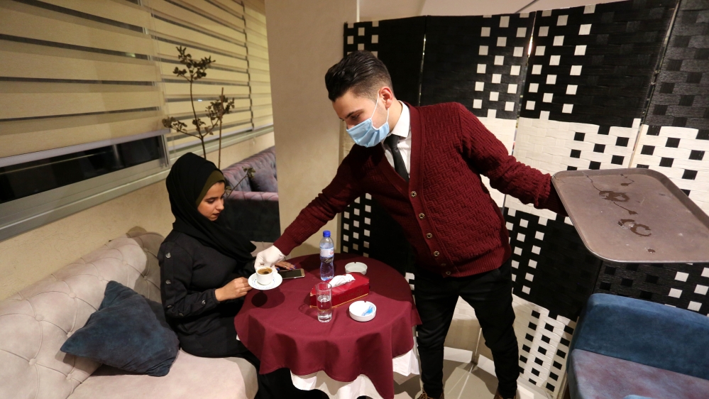 A waiter serves a cup of coffee to a customer after restaurants were reopened as part of loosening restrictions in Gaza City