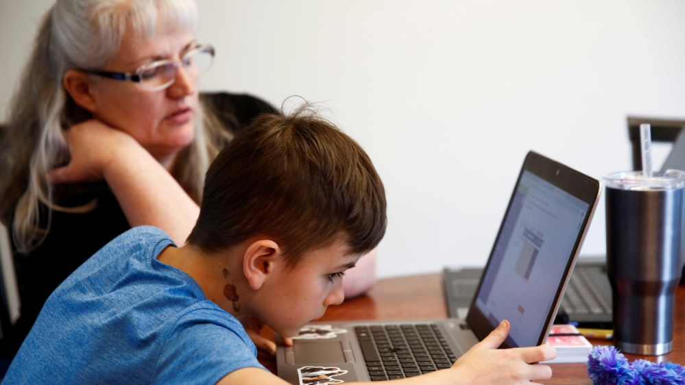 A fourth-grader trying to do a school assignment on his laptop without external speakers as he and his grandmother try to navigate the online learning system in Woodinville, Washington, US