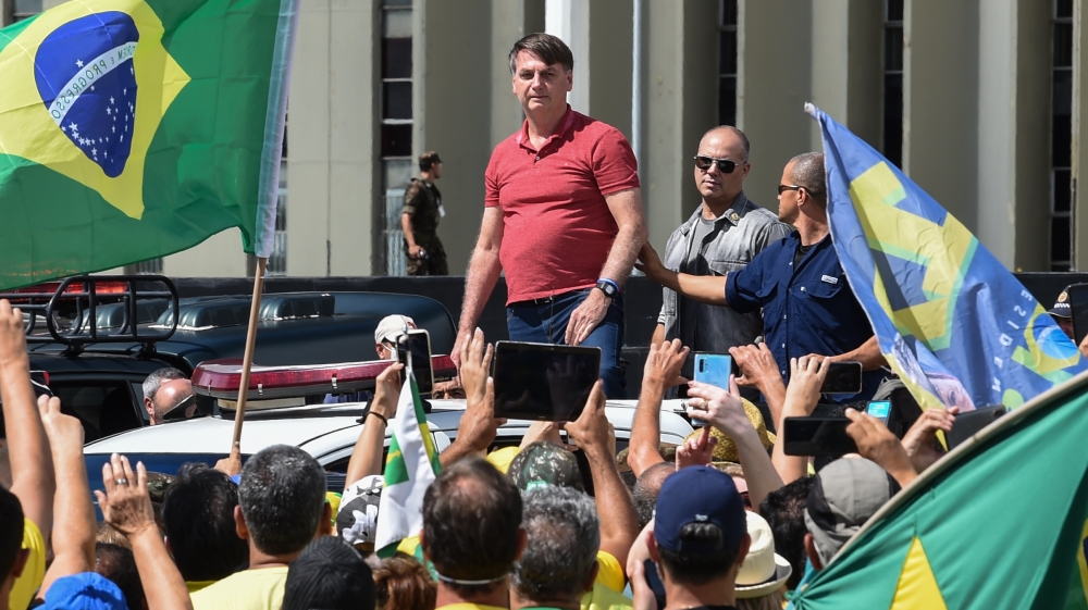 Brazilian President Jair Bolsonaro prepares to speak after joining his supporters taking part in a motorcade to protest against quarantine and social distancing measures to combat the coronavirus outbreak
