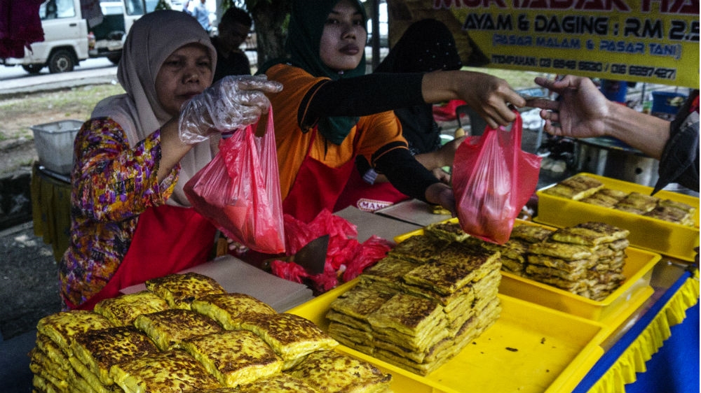 Women sell murtabak, a thin pastry filled with minced meat curry, eggs and onion at a traditional Ramadan bazaar in Kuala Lumpur