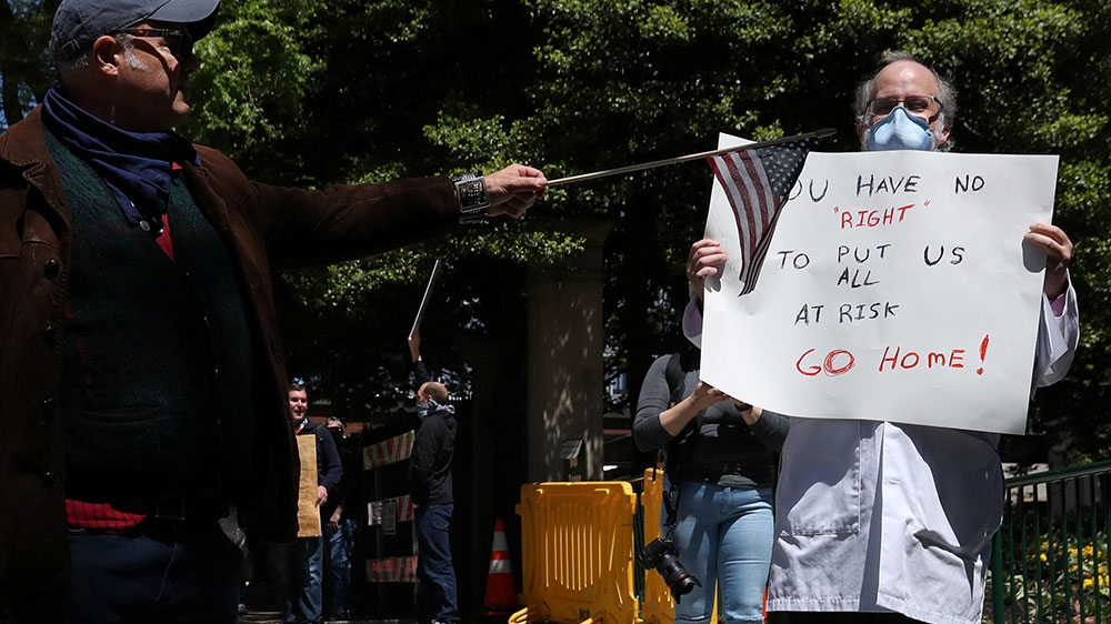 A demonstrator tries to block the sign of counter-protester Dr Erich Bruhn during a protest against lockdown measures put into place because of the coronavirus disease (COVID-19) outbreak in Richmond,