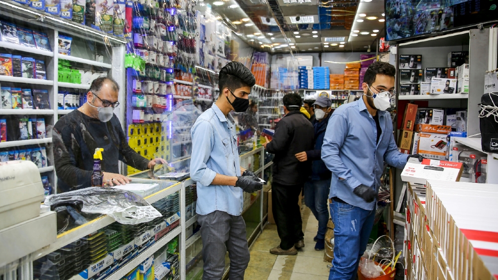 IRAN-HEALTH-VIRUS Iranian men, wearing personal protective equipment, are pictured at an electronics shop in Mashhad on April 11, 2020, amid the coronavirus (COVID-19) pandemic.