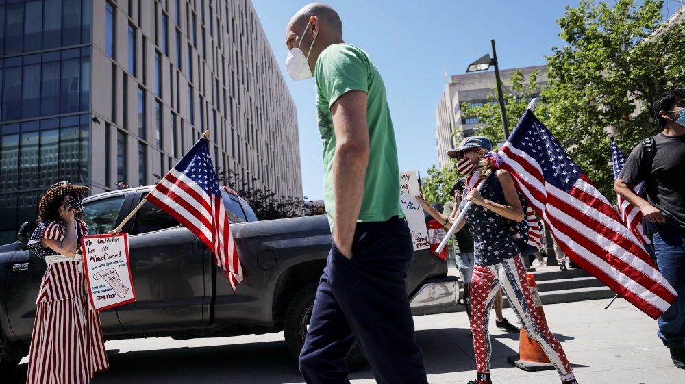 Demonstrators hold US flags as they participate in a protest outside City Hall in Los Angeles, California calling on officials to reopen the economy amid the coronavirus pandemic.