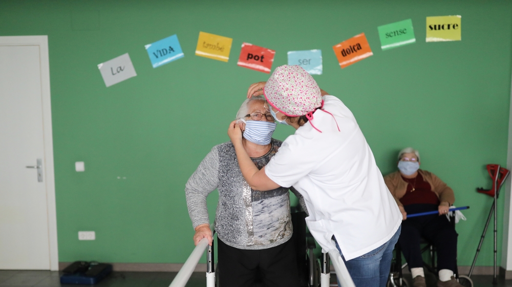 A social worker puts a protective mask on an elderly woman at a nursing home, during the coronavirus disease (COVID-19) outbreak, in Artes, near Barcelona, Spain April 30, 2020. REUTERS/Nacho Doce