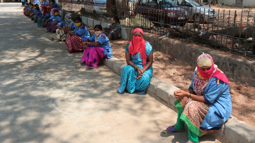 Indian municipal workers wait to collect essential commodities distributed by the government during lockdown in Hyderabad