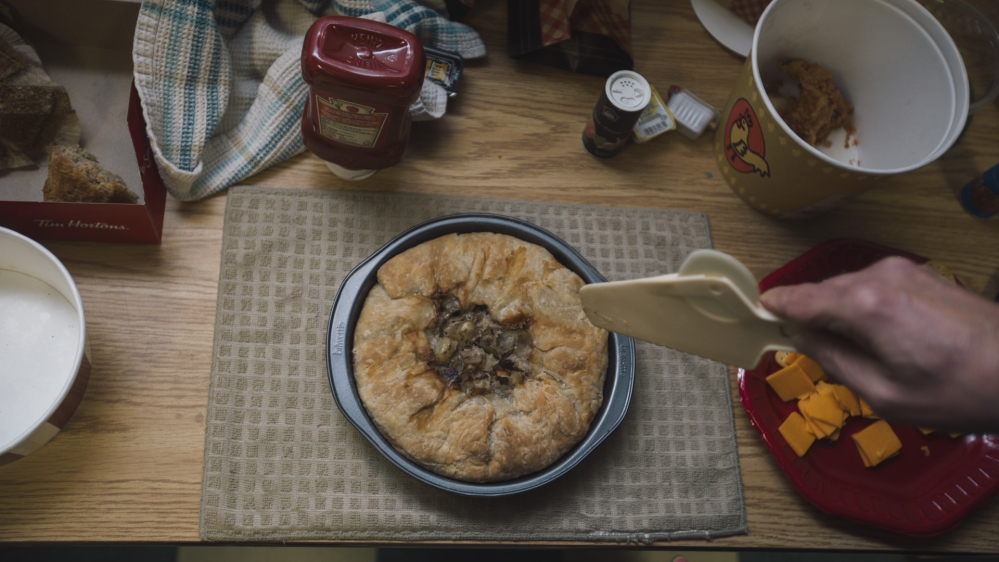 Pierre Lamoureux cuts tourtière, made with a mix of pork and moose meat, that he brought to the meeting