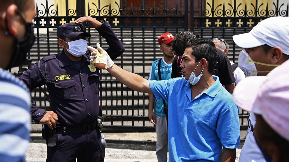 People protest in front of a policeman for the closure of the offices that distribute a subsidy granted by the state during a 30-day quarantine imposed by the government due to the coronavirus pandemic in San Salvador, El Salvador