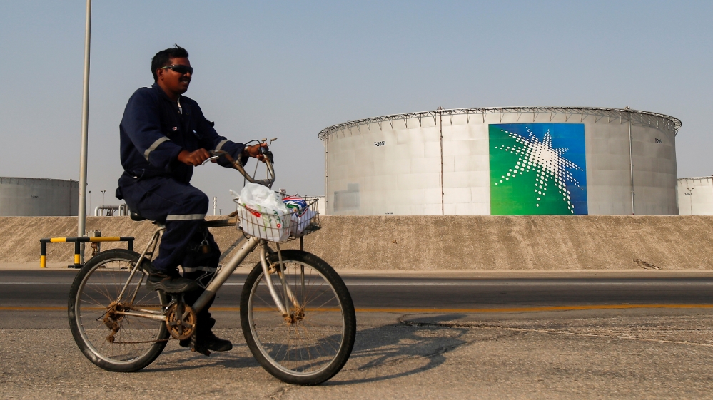 An employee rides a bicycle next to oil tanks at Saudi Aramco oil facility in Abqaiq