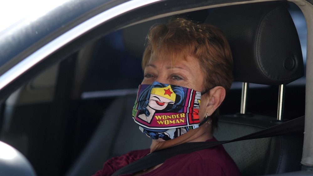 A woman wearing a Wonder Woman mask as she waits in line at a Los Angeles food bank drive-through food giveaway in Los Angeles, California, US