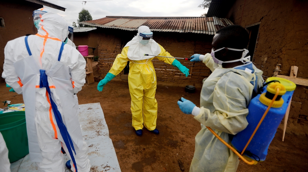 Kavota Mugisha Robert, a healthcare worker, who volunteered in the Ebola response, decontaminates his colleague after he entered the house of 85-year-old woman, suspected of dying of Ebola, in the eas