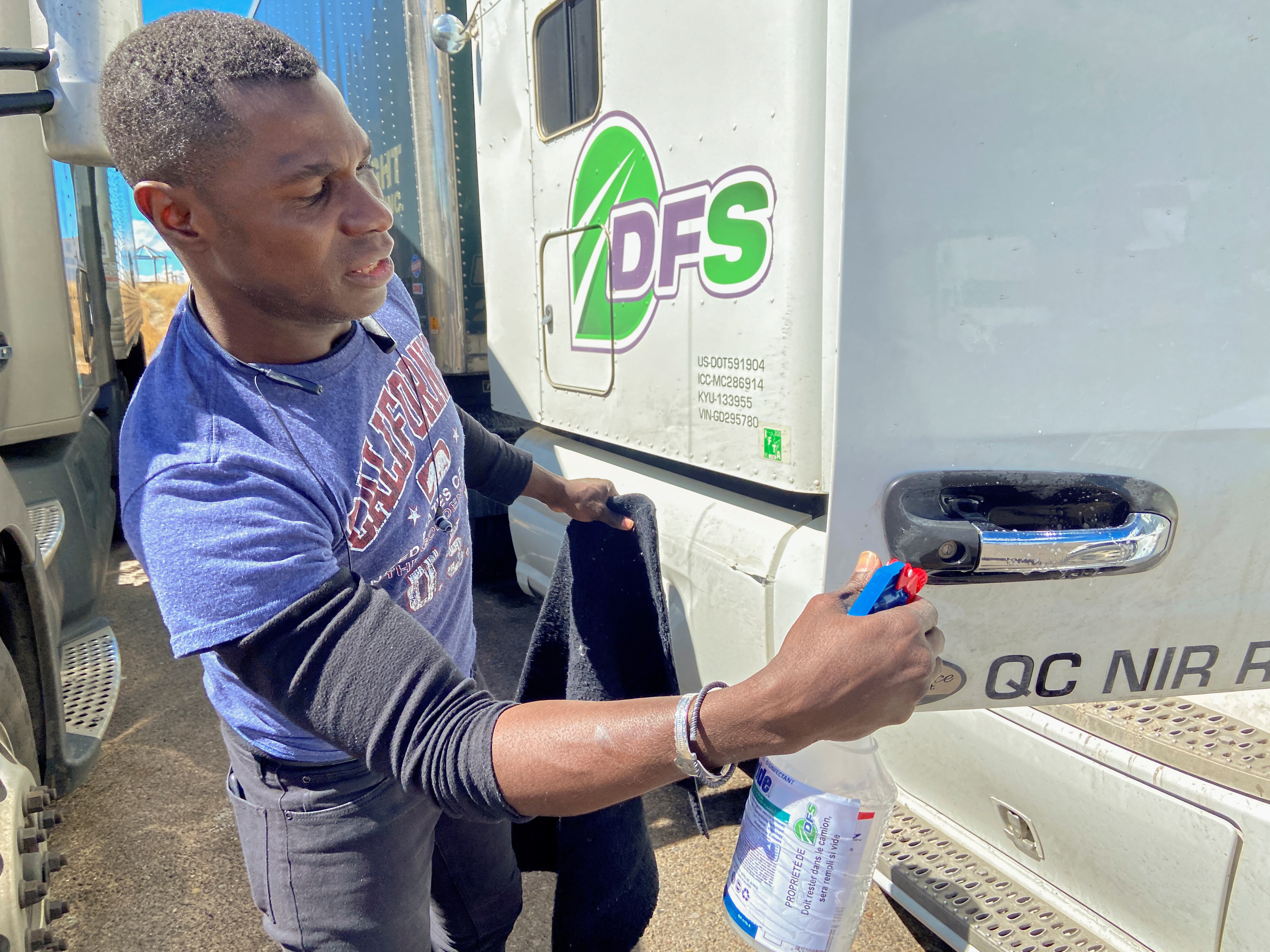 A truck driver from Canada disinfects the handle of his cab door to lower risks of spreading COVID-19 after visiting a truck stop in Las Vegas, New Mexico, US