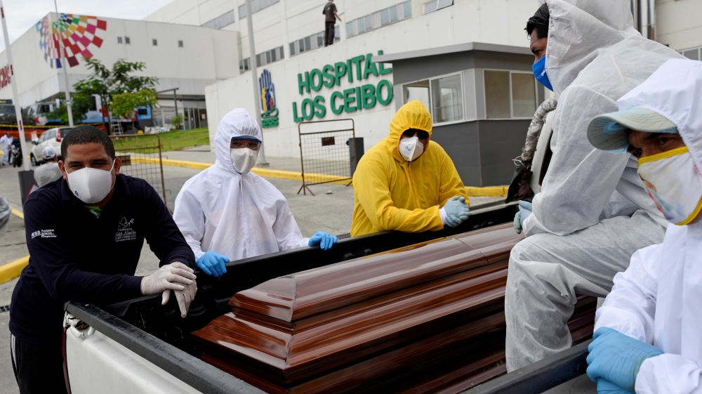 Funeral workers waiting with a coffin in the back of a pick-up truck outside Los Ceibos hospital