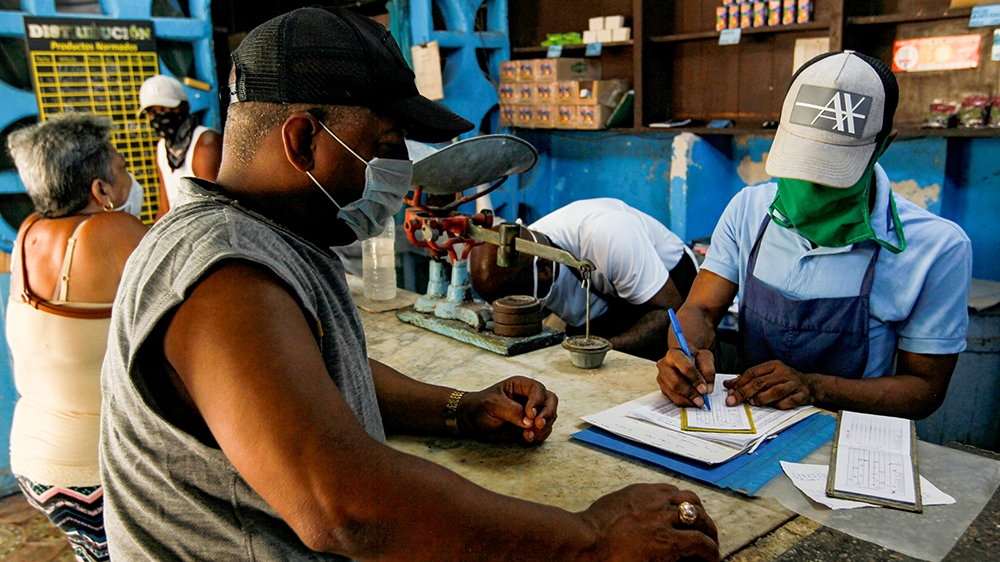 A man uses a ration book, known locally as the “libreta”, to buy goods in a subsidized state store, or “bodega”, amid the coronavirus disease (COVID-19) outbreak, in Havana, Cuba [Reuters]
