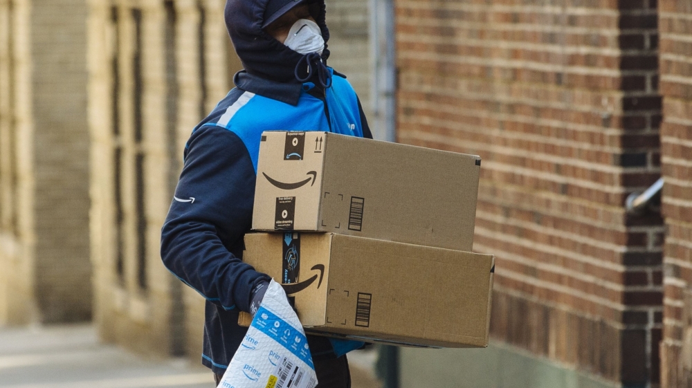 A worker carries Amazon boxes during a delivery in the Bronx, New York