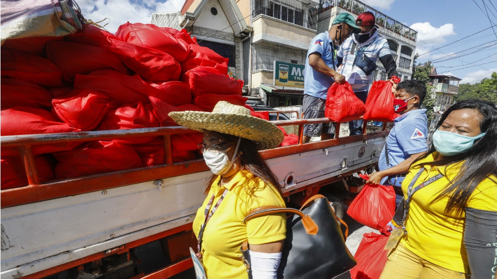 Local district workers unload bags of relief goods in a low-income community in Quezon City