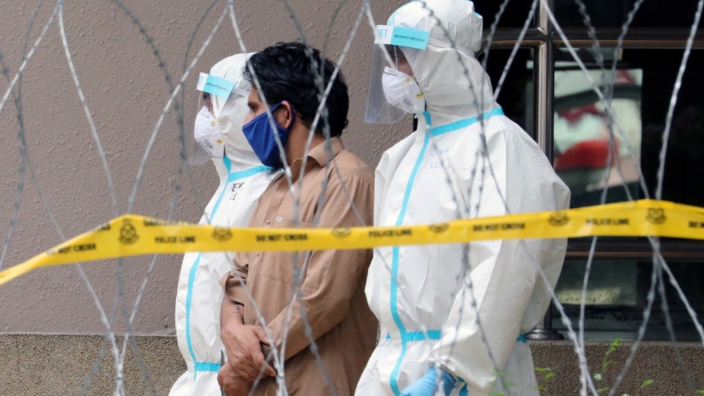 Police officers wearing protective suits pick up a migrant worker from an apartment under enhanced lockdown in Kuala Lumpur on Friday