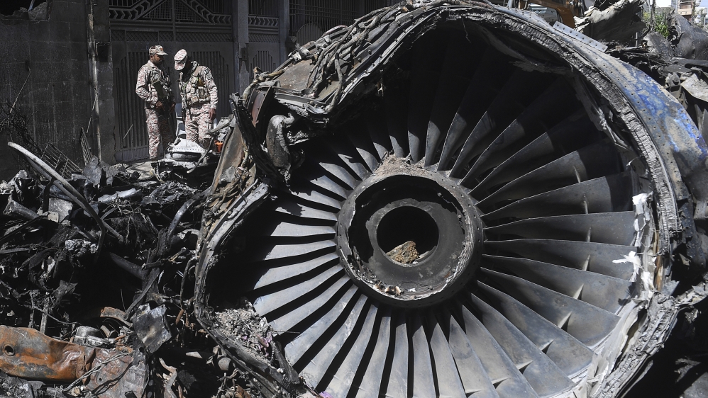 Security personnel stand beside the wreckage of a plane at the site after a Pakistan International Airlines aircraft crashed in a residential area days before, in Karachi on May 24, 2020. Ninety-seven