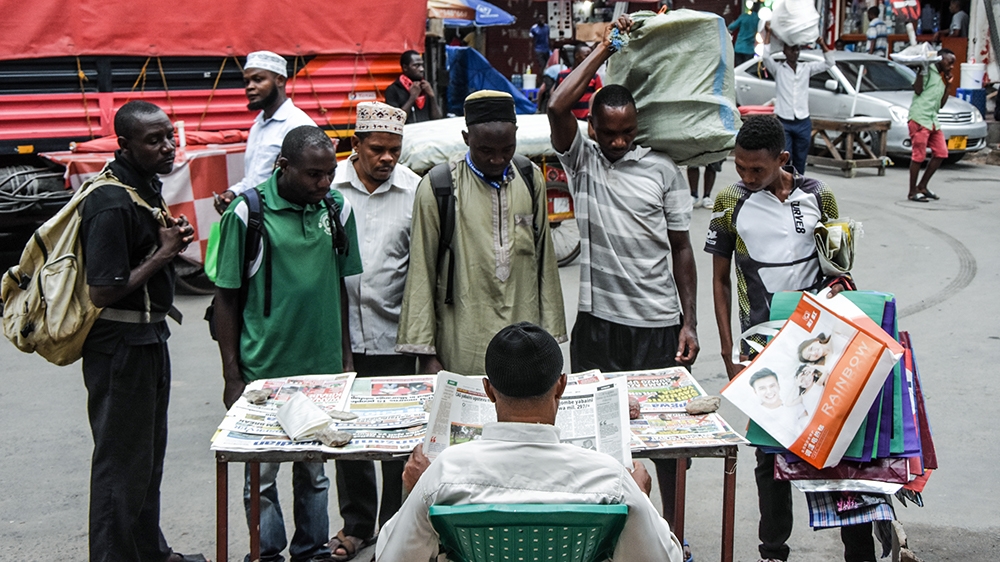People look at newspapers without adhering to physical-distancing guidelines in Dar es Salaam