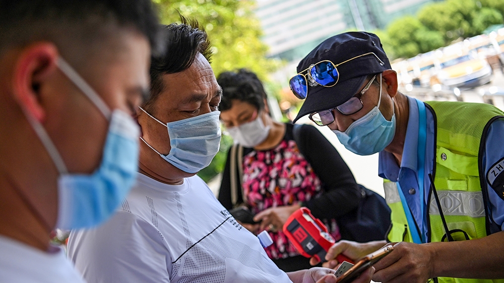 A worker checks passengers’ body temperatures and a health code on their phones before they take a taxi in Wuhan, China’s central Hubei province
