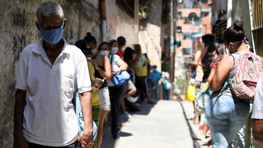 People queuing to receive food from a charity, in the slum of Carapita, during the nationwide quarantine due to the coronavirus outbreak in Caracas, Venezuela [Manaure Quintero/Reuters}
