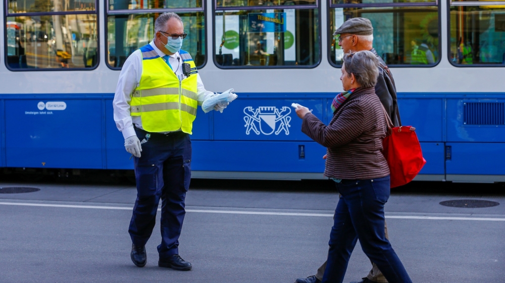 An employee of Zurich’s public transport operator Verkehrsbetriebe Zuerich (VBZ) hands out protective face masks to passengers