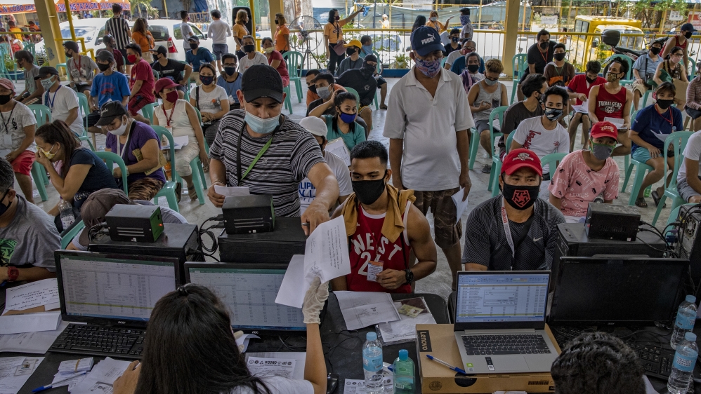 Filipinos out of work due to the coronavirus lockdown queue to receive government cash in Quezon city, Metro Manila