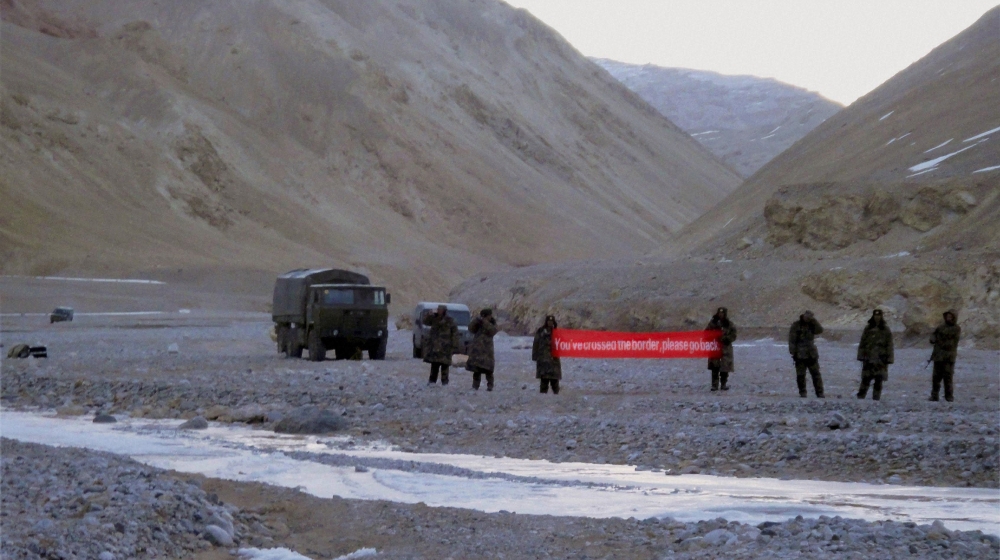 In this May 5, 2013 file photo, Chinese troop hold a banner which reads, "You''ve crossed the border, please go back," in Ladakh, India. Chinese President Xi Jinping is coming to India to meet with Pr