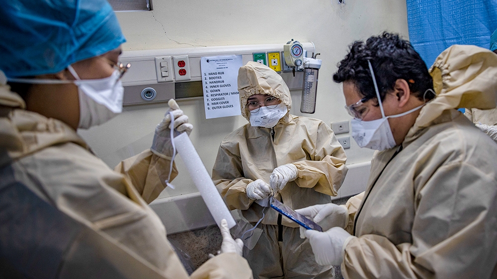 Health workers don protective clothing before treating patients at a COVID-19 isolation facility in Manila. Some nurses and doctors in the country say they have been abused or forced from their homes as a result of their work