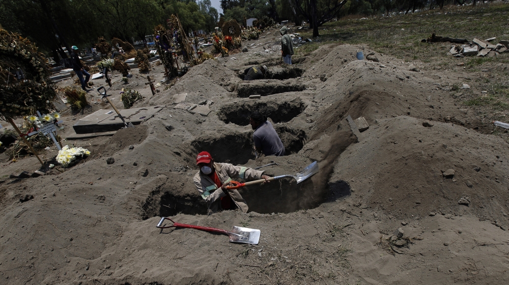 Melvin Sanaurio, front, digs a grave at the San Lorenzo Tezonco Iztapalapa cemetery in Mexico City, amid the new coronavirus pandemic. “It takes me more than an hour to dig one grave,” Sanaurio said