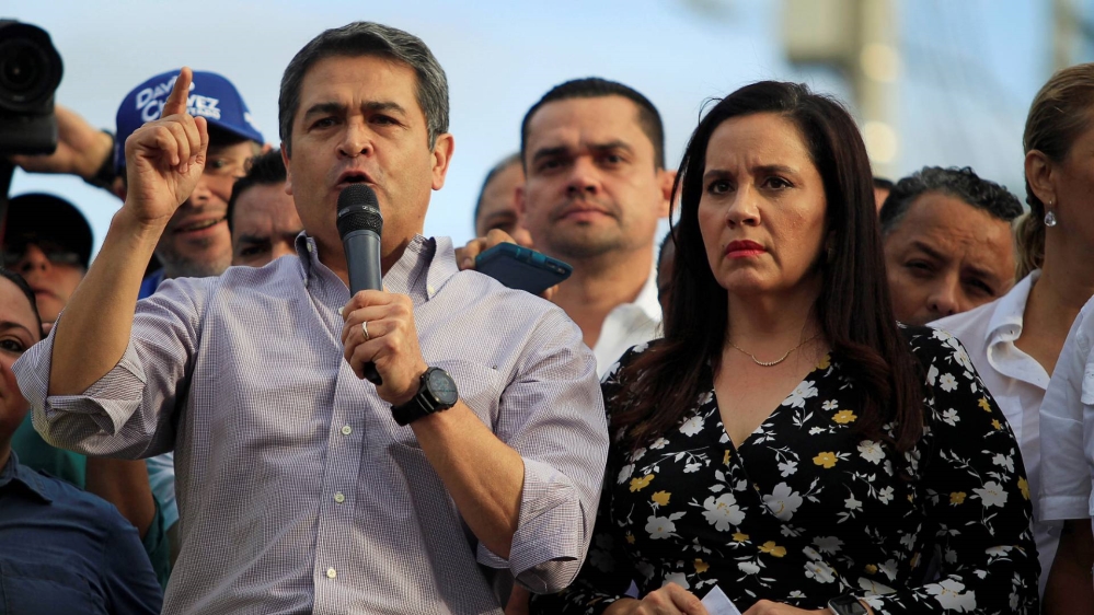 Honduran President Juan Orlando Hernandez, accompanied by his wife Ana Garcia, addresses supporters during a rally outside the Presidential House in 2019