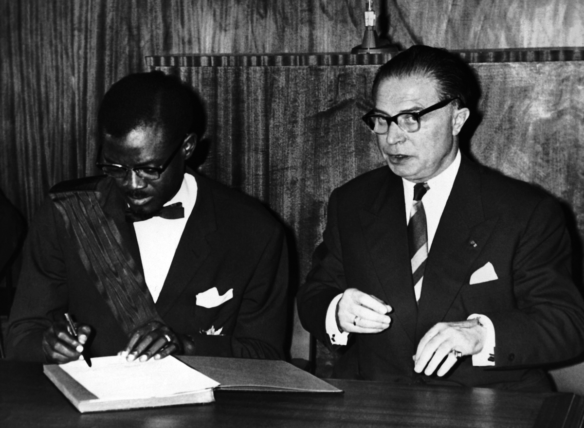 Patrice Lumumba, the Prime Minister of the Congo, signs the act of independence of the Congo in Leopoldville, Congo on June 30, 1960. At right is Gaston Eyskens, Prime Minister of Belgium, who signed