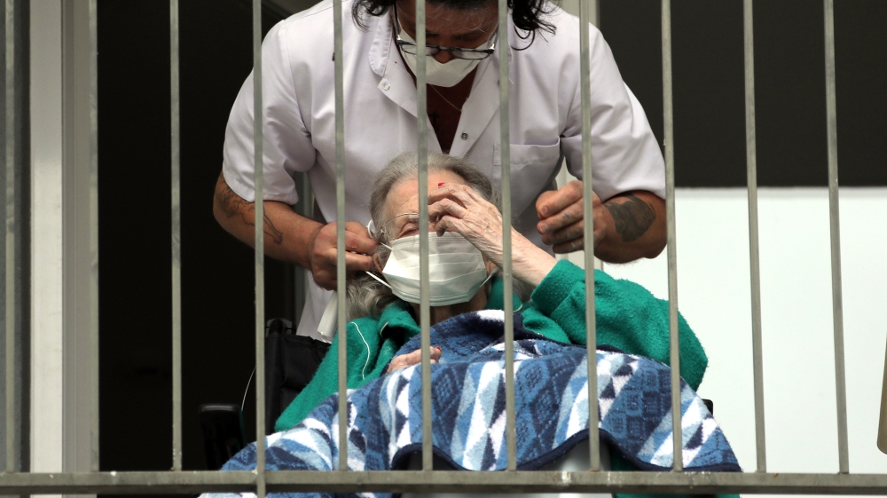 A nurse adjusts a protective mask on the face of a resident at “La Residence des Anciens Combattants” retirement home