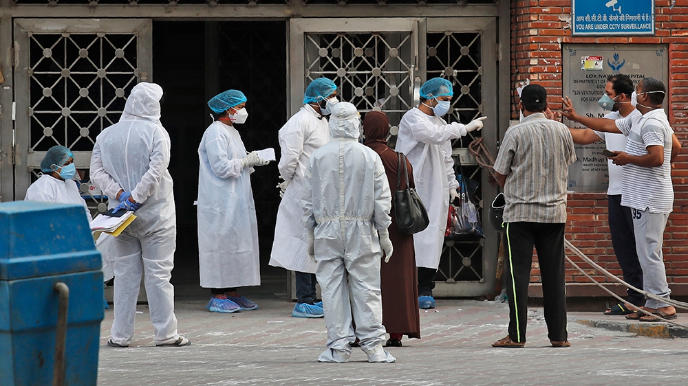 Health workers talk to people accompanying a patient at a hospital that treats COVID-19 patients in New Delhi