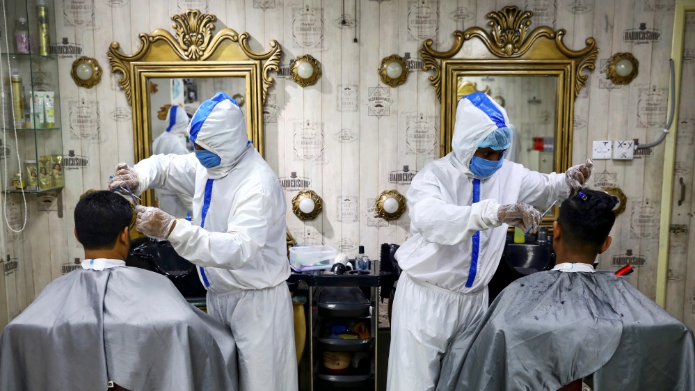 Barbers wearing protective suits and face masks provide hair cuts to customers inside a salon amid the coronavirus pandemic in Dhaka