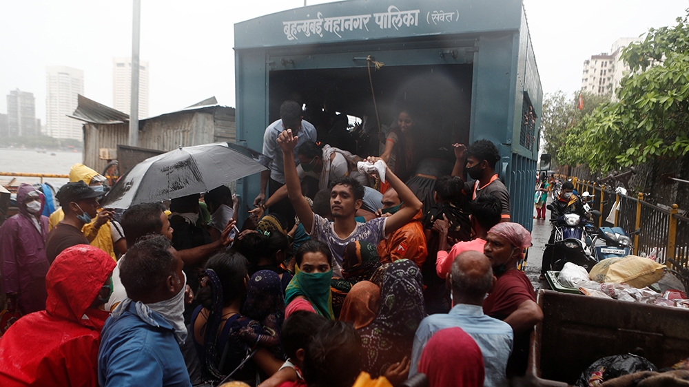 People scramble to enter a truck during an evacuation of a slum in Mumbai as Cyclone Nisarga makes its landfall