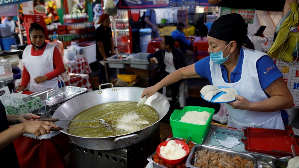 Sabina Hernandez Bautista, 59, prepares food in a stall inside Mexico City’s Mercado de San Cosme, where some vendors have put in place their own protective measures against coronavirus while others continue to work without masks or barriers
