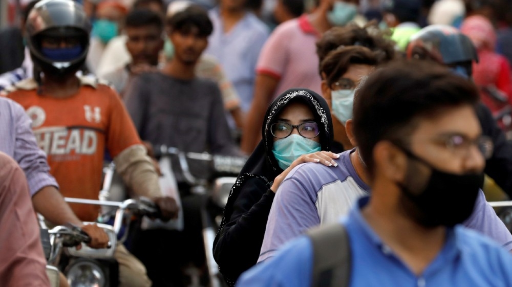 A woman rides on a motor bike as she wears a protective face mask amid the rush of people outside a market as the outbreak of the coronavirus disease (COVID-19) continues, in Karachi, Pakistan