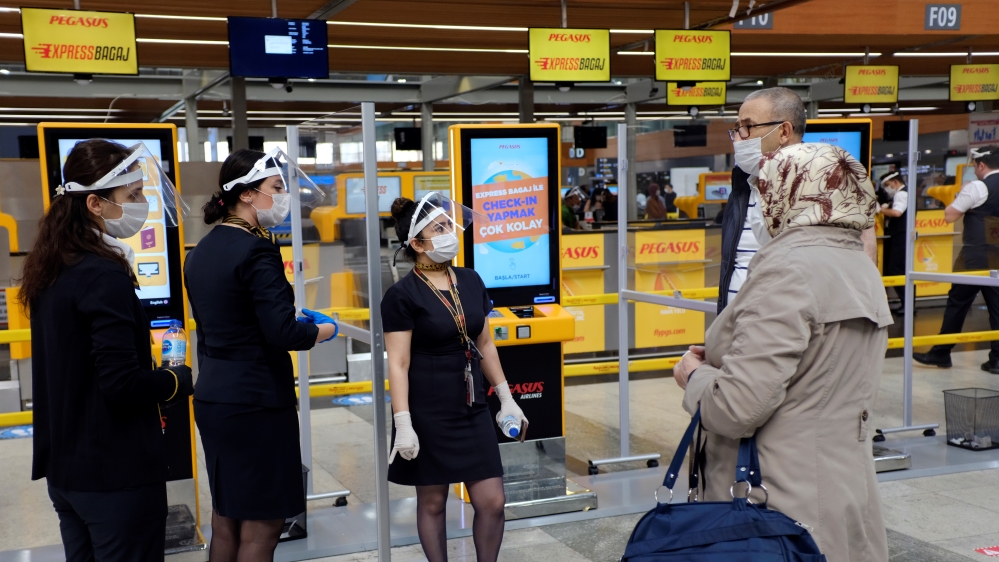 Pegasus Airlines employees wearing protective masks and face shields inform passengers at the domestic departure terminal of Sabiha Gokcen Airport in Istanbul, Turkey June 11, 2020.