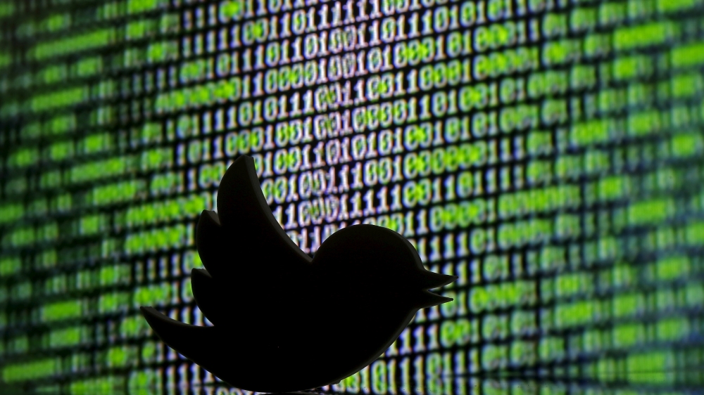 3D printed Twitter logo is seen in front of a displayed cyber code
