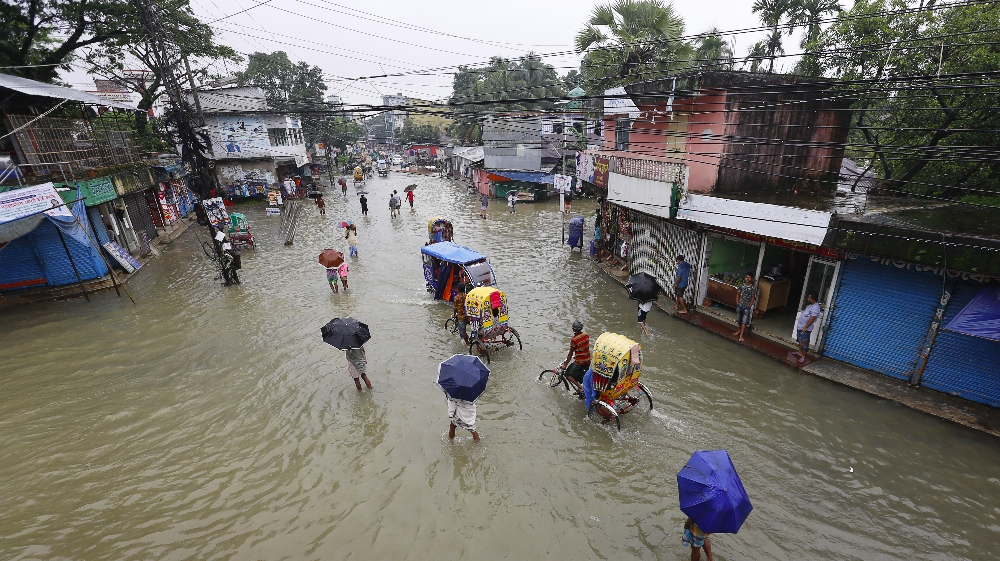 BANGLADESH-FLOOD-WEATHER In this photograph taken on July 12, 2020, people make their way through flood waters in Sunamgong. Sultan Mahmud / AFP