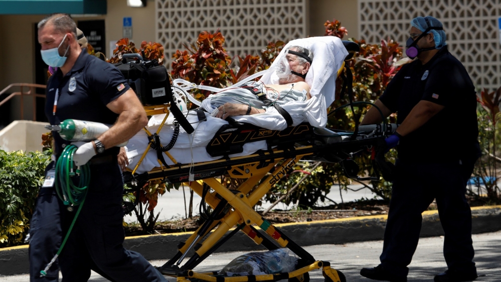 Emergency Medical Technicians (EMT) leave with a patient at Hialeah Hospital where the coronavirus disease (COVID-19) patients are treated