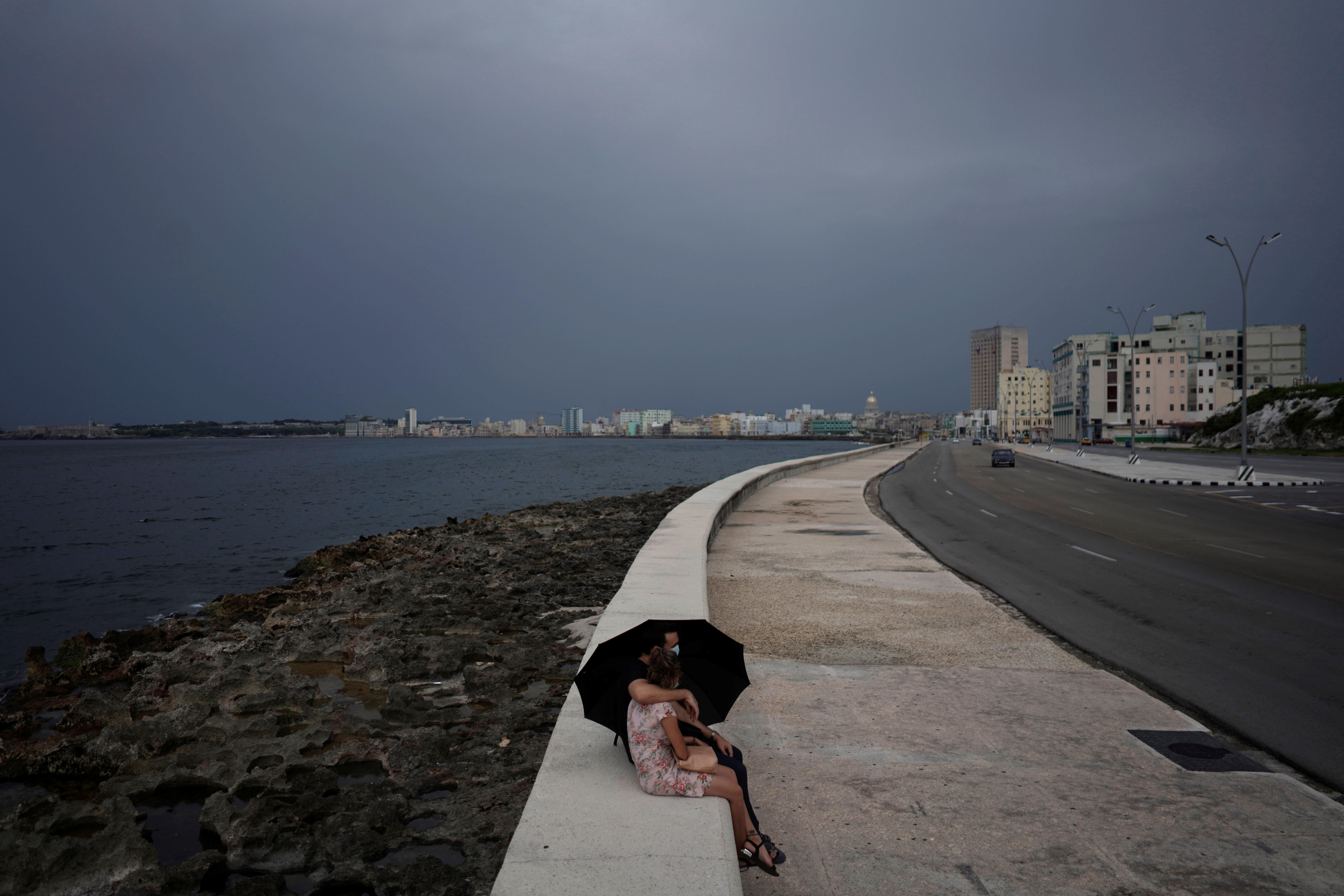 A couple sits at the seafront Malecon in Havana, Cuba