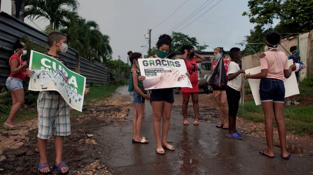 Residents of Havana hold banners as they wait for the arrival of the Cuban medical personnel, who volunteered in the fight against coronavirus in the European principality of Andorra