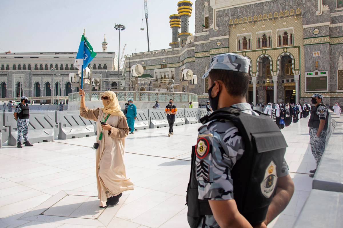 In this photo released by the Saudi Media Ministry, security personnel standby as a limited numbers of pilgrims arrive keeping social distancing to limit exposure and the potential transmission of the