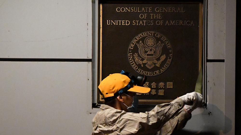A worker attempts to remove the plaque on the wall outside the US consulate in Chengdu on Sunday